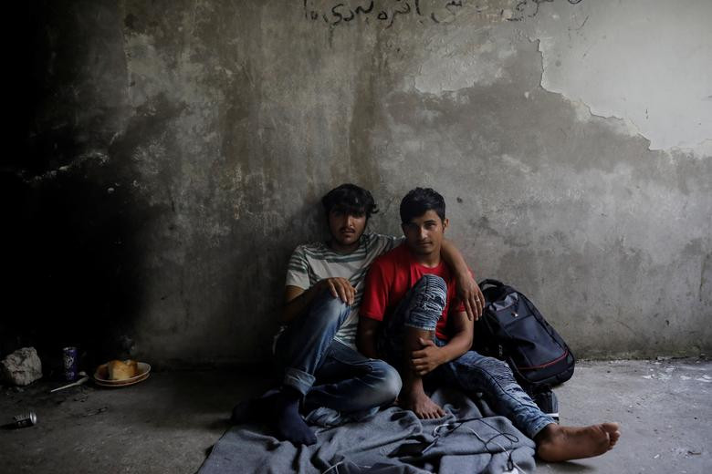 Hai di dân Afghanistan ngồi nghỉ trong một nhà máy in bỏ hoang tại khu vực gần biên giới Serbia-Croatia hôm 19/6.