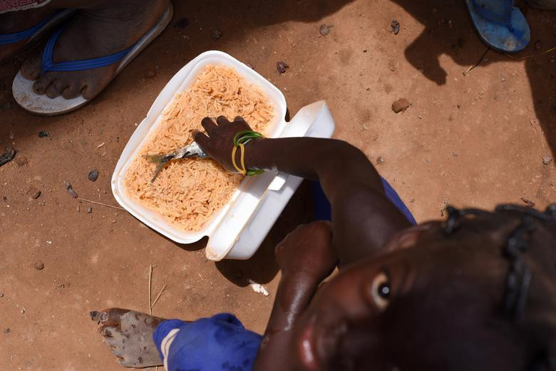 Một em nhỏ ngồi ăn trong ngôi trường ở ngoại ô Ouagadougou, Burkina Faso, ngày 15/6.