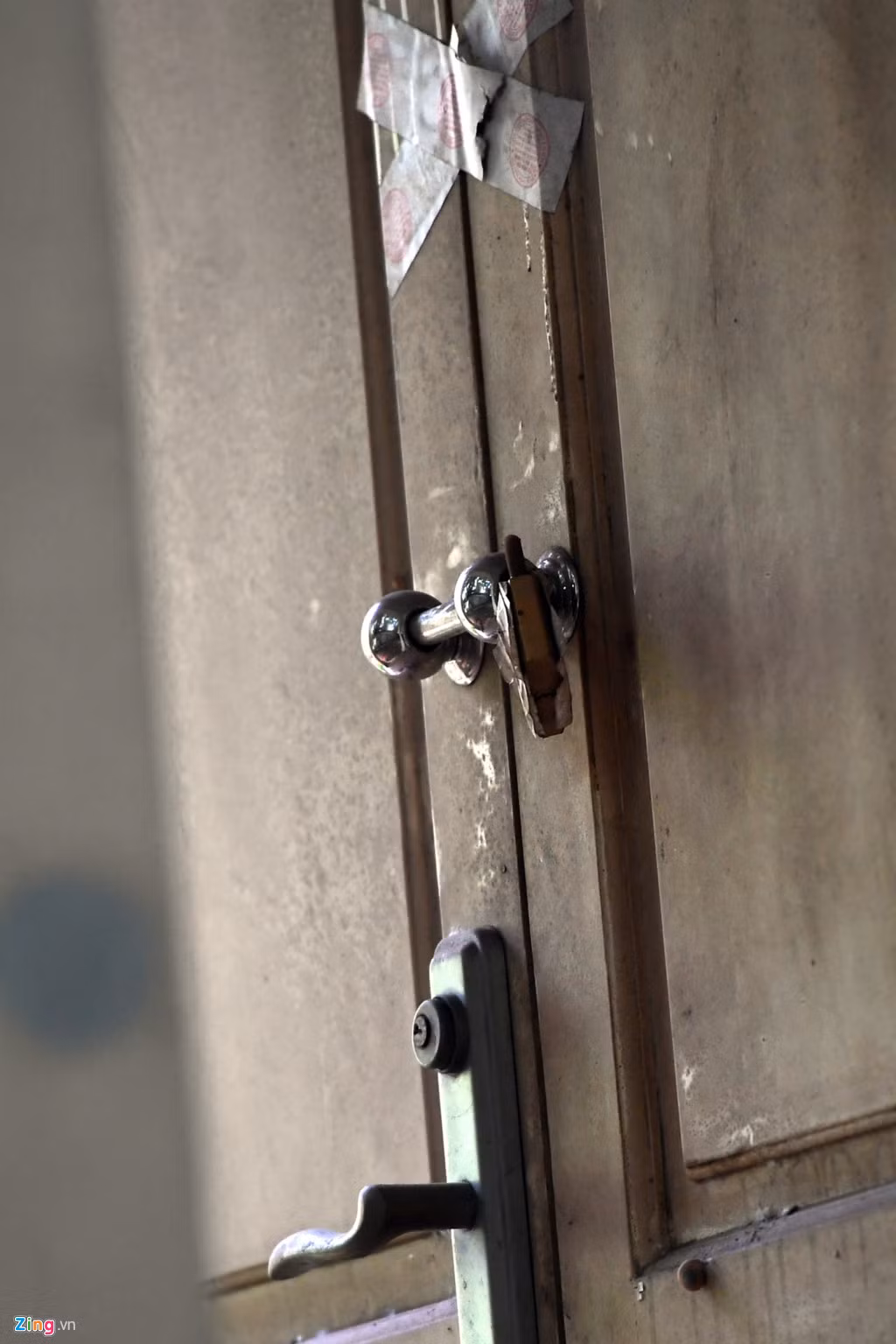 Cửa chính của căn nhà được khoá kín, giấy niêm phong vẫn dính chặt nhưng không còn nguyên vẹn.