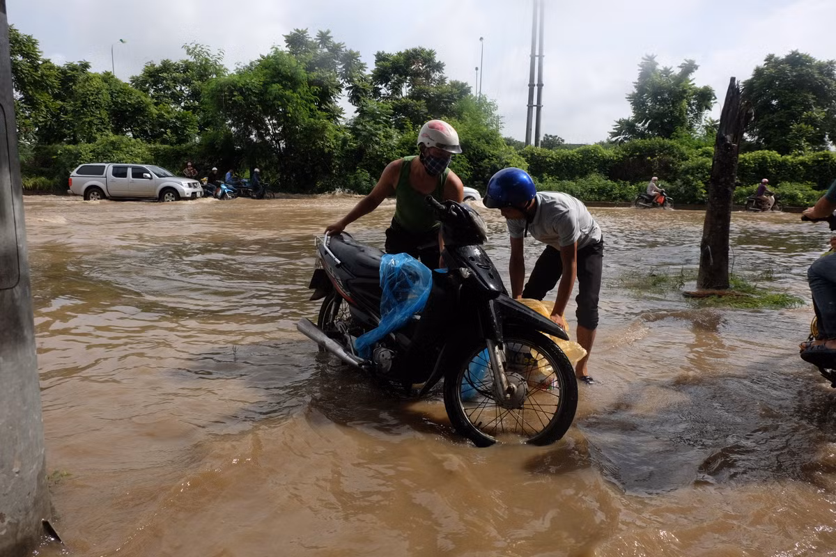 Hai người đàn ông phải khiêng xe máy lên vùng ít ngập hơn.