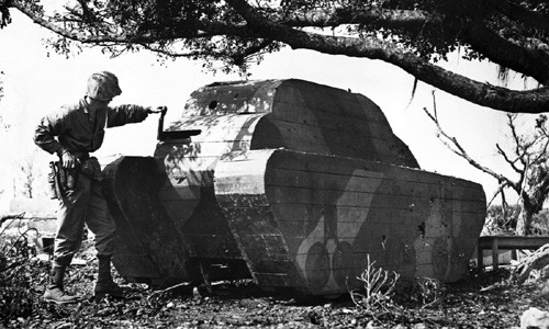 Một lính Mỹ đứng bên cạnh một xe tăng làm từ gỗ của quân đội Nhật Bản được phát hiện ở Okinawa.