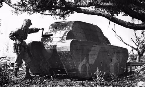 Một lính Mỹ đứng bên cạnh một xe tăng làm từ gỗ của quân đội Nhật Bản được phát hiện ở Okinawa.