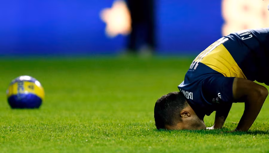 Tiền đạo Carlos Tevez của đội tuyển quốc gia Argentine hôn xuống nền sân cỏ để cầu nguyện trước trận đấu.