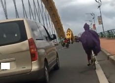 Ôtô chắn gió cho xe đạp qua cầu ở Đà Nẵng. Ảnh cắt từ clip.