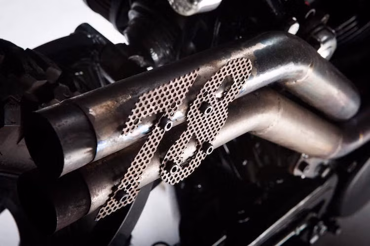 Những ống xả được chế tác thủ công, vắt cao theo đúng phong cách Scrambler với con số 78 cắt từ lưới thép được gắn lên.