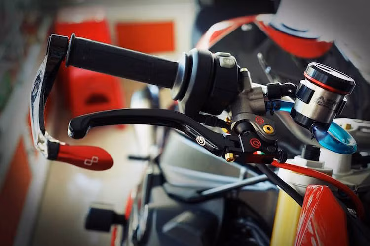 Nằm trên ghi đông là cùm phanh Brembo Rossi, bình dầu của AEM và vòng bảo vệ tay phanh gắn gù của LighTech.