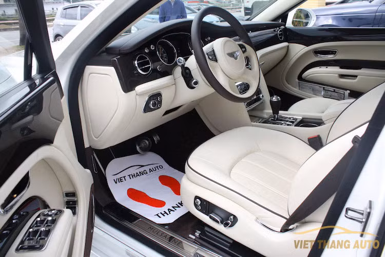 Mở cánh cửa xe ra, nội thất của Mulsanne phô bày trước mắt. Chiếc xe này đã được đặt hàng qua chi nhánh cá nhân hóa Mulliner của Bentley để có nội thất bọc da màu trắng thanh khiết.