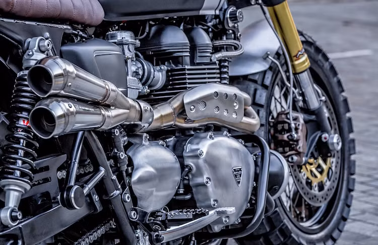 Ống xả trên chiếc xe là dạng "pô vắt" đúng phong cách Scrambler, treo ở bên phải thân xe và có kết cấu 2-1-2. Toàn bộ phần pô và cổ pô đều do Shaun chế tác thủ công.