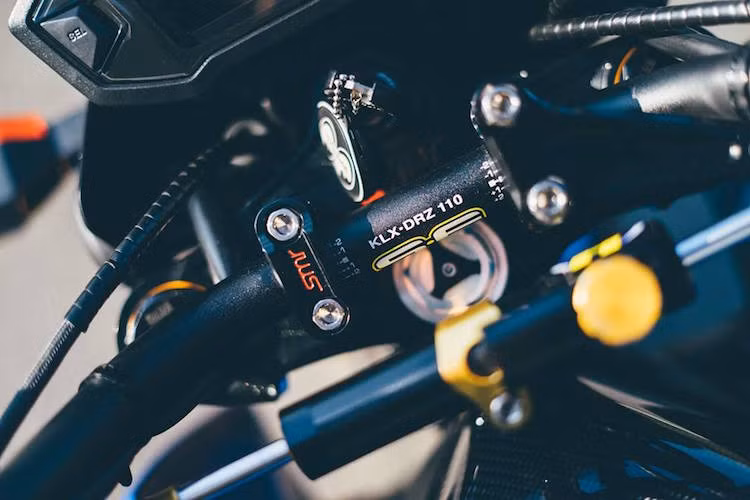 Gù tay lái kèm theo ghi-đông được thay bằng loại của hãng SMR và vốn dành cho mẫu minibike của Kawasaki là KLX110. Ở phía trên là cây trợ lực "kiểng".
