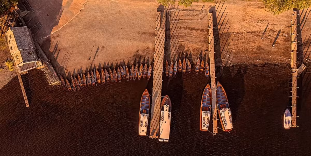 Khoảnh khắc hoàng hôn trên mặt hồ Derwent ở Cumbria với những chiếc thuyền nhiều màu sắc neo đậu san sát bên bờ và các cầu tàu phía tây bắc nước Anh.
