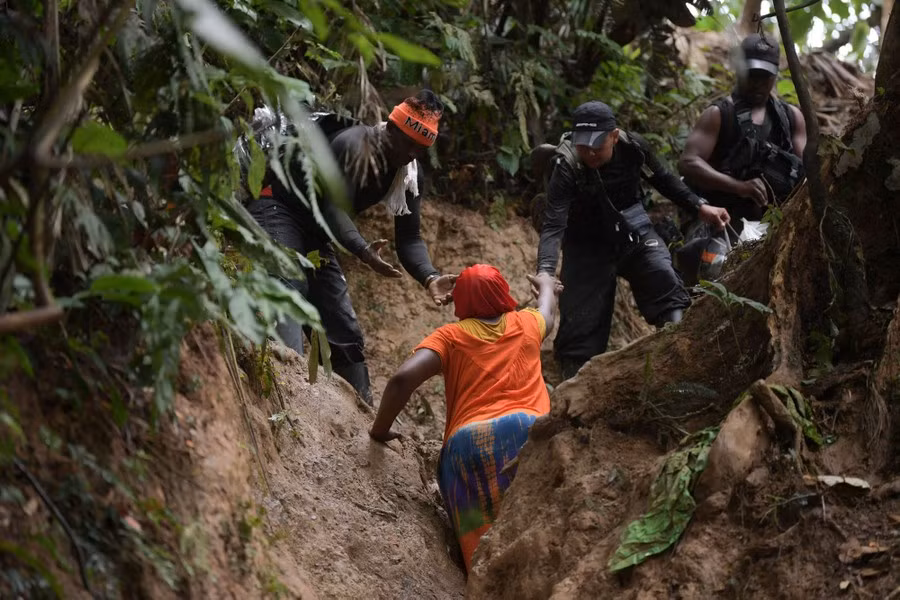 Một phụ nữ Haiti được những người di cư giúp đỡ trên con đường lầy lội trong rừng rậm Darien Gap, gần Acandi.