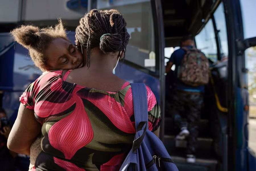 Một đứa trẻ ngủ trên vai mẹ khi họ chuẩn bị lên xe buýt đến San Antonio, ngay sau khi một nhóm người di cư, trong đó có nhiều người Haiti, được thả khỏi nơi giam giữ khi vượt qua biên giới Texas-Mexico để tìm nơi tị nạn. Ảnh: Theatlantic.