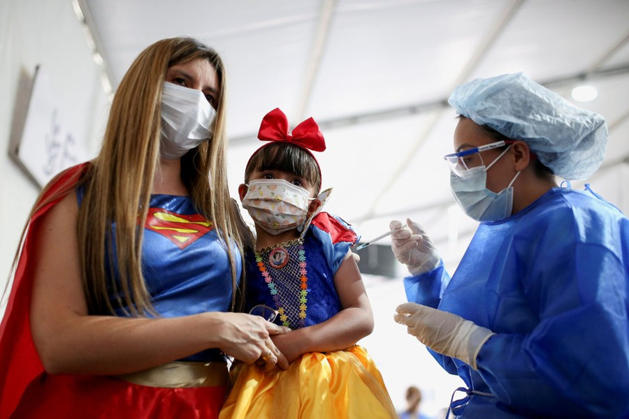 Một phụ nữ Colombia và con gái của cô ấy xuất hiện trong trang phục Superman khi được tiêm chủng vaccine Sinovac phòng COVID-19 đầu tiên của Trung Quốc. Chính phủ nước này bắt đầu chiến dịch tiêm chủng cho trẻ em từ ngày 31/10/2021.