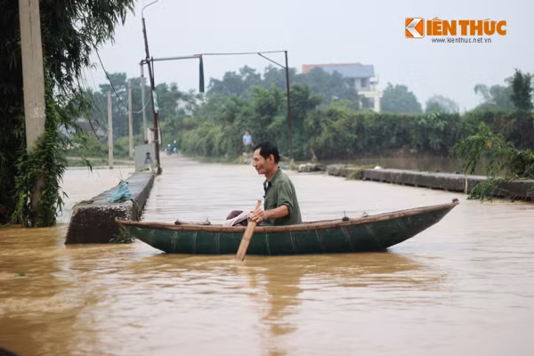 Không đi bộ được qua nước lũ, người dân sử dụng thuyền để di chuyển.