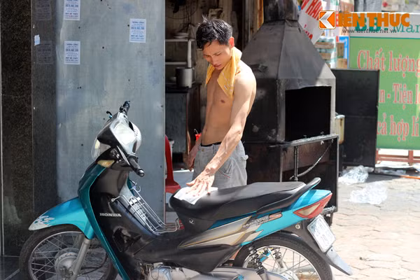Nam thanh niên nhăn nhó vì dùng khăn ướt lau mấy lần mà yên xe chưa hết nóng để có thể ngồi lên.