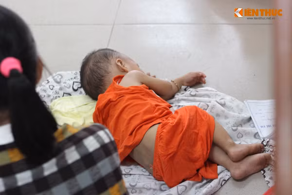 Em bé nằm ngủ ngon lành trên chiếc áo chống nắng mà người mẹ trải ngay dưới sàn đá của Bệnh viện Nhi Trung ương.