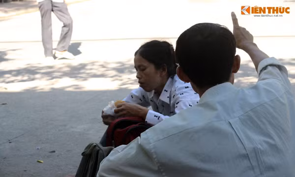 Một phụ huynh tranh thủ nhai miếng bánh mỳ, lót dạ vì vội vàng đưa con đi thi chưa kịp ăn sáng.