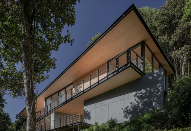 Tường chắn bê tông được sử dụng để giúp định hình địa hình ở Cunco, Chile, nơi có ngôi nhà này của Triangular Arquitectos.