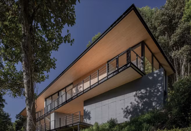 Tường chắn bê tông được sử dụng để giúp định hình địa hình ở Cunco, Chile, nơi có ngôi nhà này của Triangular Arquitectos.