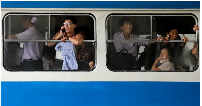 Người đàn ông nói chuyện qua điện thoại di động khi đứng trên xe điện qua trung tâm Bình Nhưỡng.