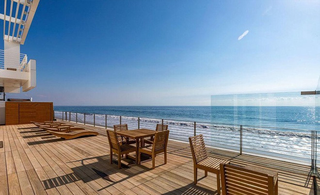 Hiên nhà với khu vực ăn uống và khu vực tắm nắng. Bất động sản này còn bao gồm một nhà để xe rộng rãi và một bờ biển riêng dài khoảng 32 m.