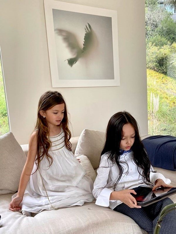 Phòng khách của Hồng Nhung không sử dụng nội thất gỗ như khu vực đặt bàn ăn. Thay vào đó, bộ sofa mút bọc vải trắng tinh là chỗ thư giãn lý tưởng. Giá sách ốp tường kế bên, trưng bày một số cuốn đặc sắc. Ngồi tại đây có thể ngắm cảnh ngoài vườn, đọc sách hay nghe nhạc.