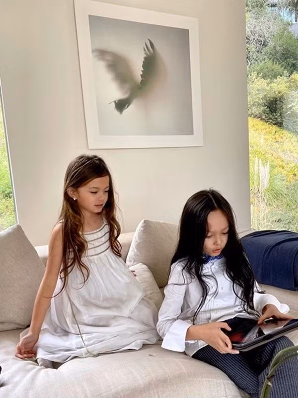 Phòng khách của Hồng Nhung không sử dụng nội thất gỗ như khu vực đặt bàn ăn. Thay vào đó, bộ sofa mút bọc vải trắng tinh là chỗ thư giãn lý tưởng. Giá sách ốp tường kế bên, trưng bày một số cuốn đặc sắc. Ngồi tại đây có thể ngắm cảnh ngoài vườn, đọc sách hay nghe nhạc.