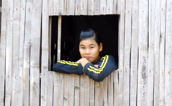 Thiếu nữ miền Tây bên khung cửa sổ của ngôi nhà tre nứa đặc trưng vùng sông nước.