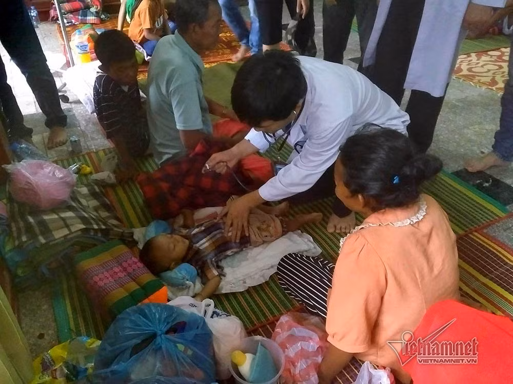 Bác sĩ nghe khám phổi cho em bé 9 tháng tuổi vừa thoát khỏi lũ dữ