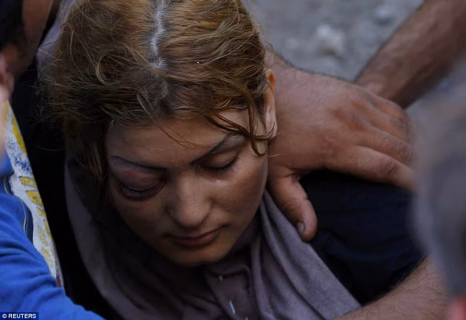 Một bé gái nép vào lòng mẹ, gương mặt hằn lên vẻ khiếp sợ khi chứng kiến vụ ẩu đả tại nhà ga Beli Manastir, phía bắc Croatia.