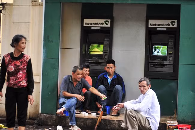 Những người dân lao động ngồi trong một cây ATM trên đường Chu Văn An (Ba Đình), uống trà nóng và hút thuốc lào để tránh rét.