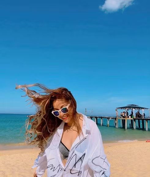 Cụ thể trong loạt ảnh mới của mình, Nhật Lê diện bikini một mảnh màu đen và khoác áo sơ mi trắng trong suốt bên ngoài.