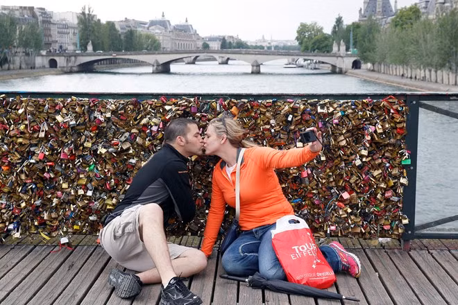 Cặp đôi trao nhau nụ hôn cuối trên cầu khóa tình yêu tại Pont des Arts, Paris. Cây cầu này đã được chính quyền thành phố Paris giải cứu bằng cách cắt bỏ hết những chiếc khóa này.