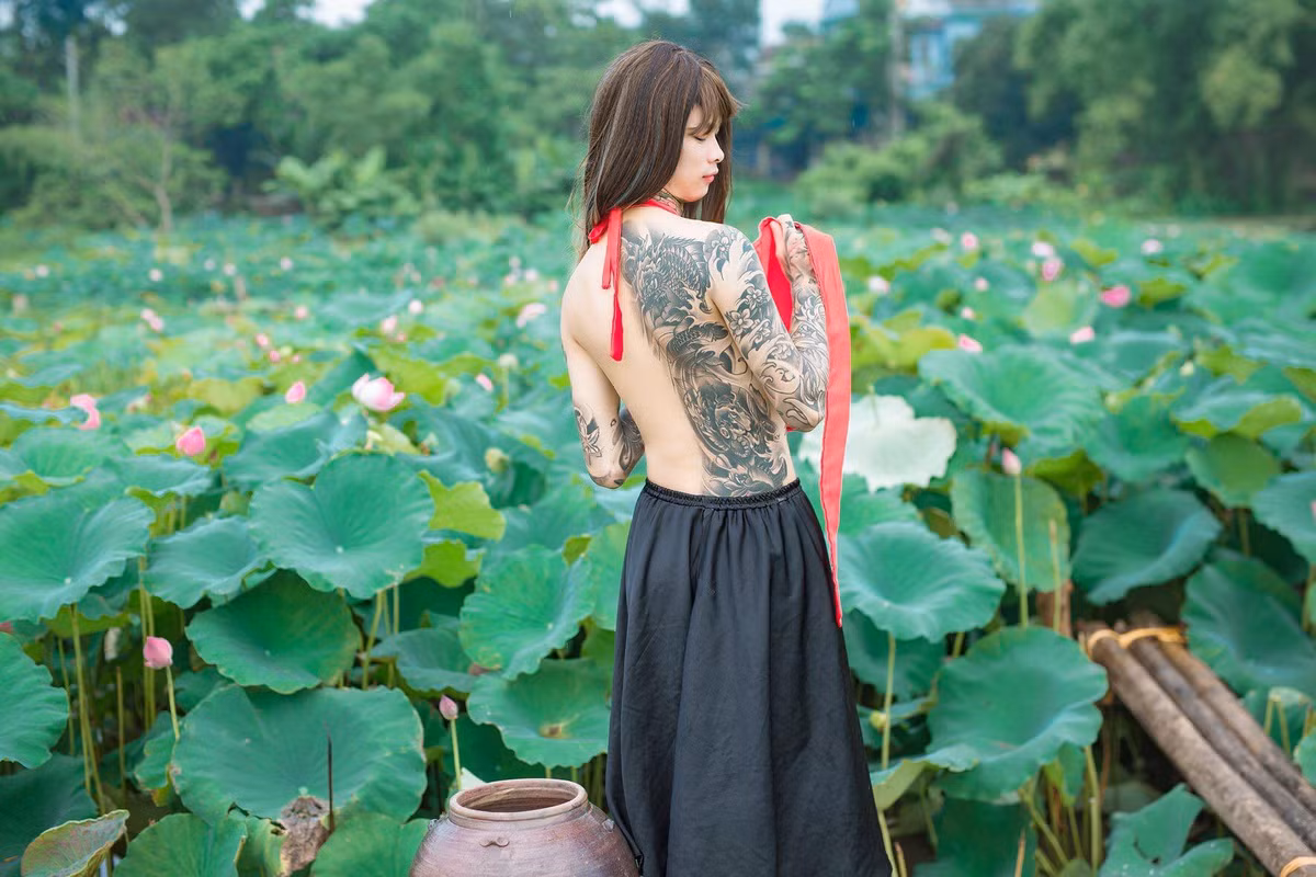 Hình ảnh một nam sinh xăm trổ, đội tóc giả, khoe lưng trần bên ao sen nhanh chóng trở thành chủ đề nóng trên mạng xã hội. Theo tìm hiểu của dân mạng, chàng trai này có tên Tuấn Lâm, hiện sinh sống tại Việt Trì và làm nghề xăm nghệ thuật.