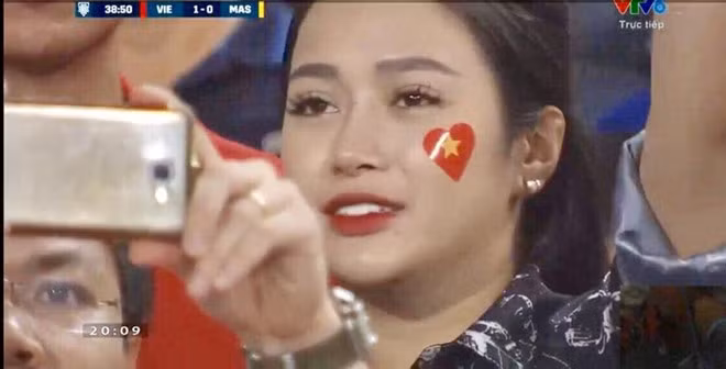 Cũng trong trận đội tuyển Việt Nam gặp Malaysia ngày 16/11, khoảnh khắc Vũ Thị Trang (23 tuổi) giơ điện thoại lên chụp ảnh cũng thu hút nhiều sự chú ý. 9X đã tốt nghiệp đại học và có công việc kinh doanh của riêng mình.