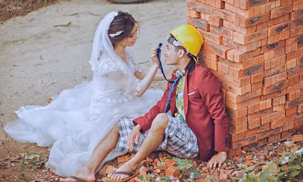 Trong ảnh cưới để đời, cô dâu Thúy Hạnh xinh đẹp mặc áo cưới tinh khôi đi chân đất để cùng chú rể Quốc Viết đóng comple, mặc quần đùi ca-rô, đội mũ bảo hộ lao động và đi dép tông cùng diễn xuất.