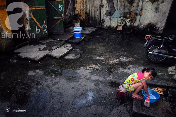 Một em bé đang giặt đồ, tò mò trước ống kính của một người khách xa lạ.