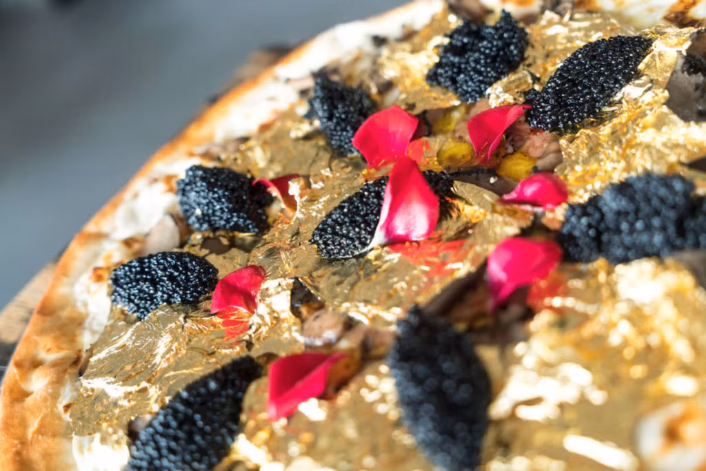 Chiếc pizza có giá 2.000 USD của nhà hàng Industry Kitchen trên phố South Street Seaport ở Manhattan (New York, Mỹ) được giới thiệu vào cuối năm 2016. Bánh được làm từ những nguyên liệu cao cấp như phô mai Stilton trắng, gan ngỗng, nấm truffle của Pháp, trứng cá muối Osetra và được trang trí bằng những miếng vàng lá. Ước tính giá cho mỗi một lần cắn là 50 USD và thực khách phải đặt trước ít nhất hai ngày nếu muốn được thưởng thức chiếc bánh này. Ảnh: Industry Kitchen.