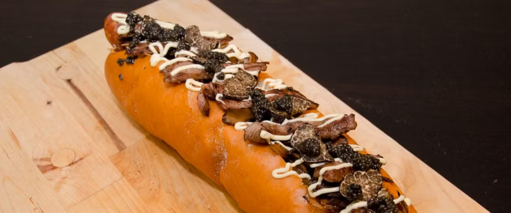 Chiếc bánh hot dog có tên là Juuni Ban của nhà hàng Dog Tokyo, Seattle (Mỹ), được chế biến mang hương vị đặc trưng của Nhật Bản bằng cách nướng một pho mát xúc xích bratwurst xông khói cùng với thịt bò Wagyu, nấm maitake, gan ngỗng, nấm truffles đen, trứng cá muối, và mayonnaise Nhật Bản. Một chiếc bánh có giá lên tới 169 USD và thực khách phải đặt trước ít nhất hai tuần. Ảnh: Tokyo Dog.