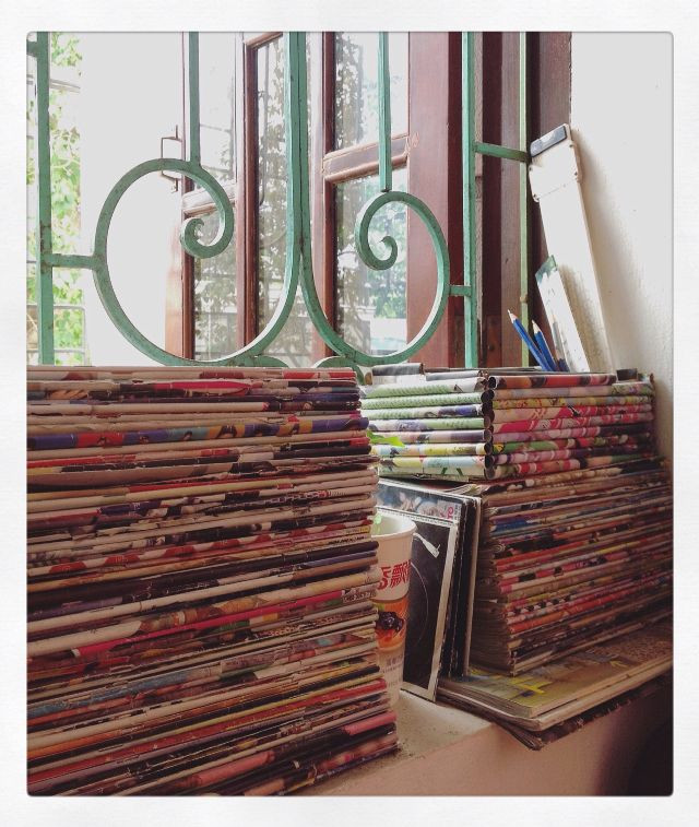 Hàng tập báo cao ngất được xếp bên khung cửa sổ.