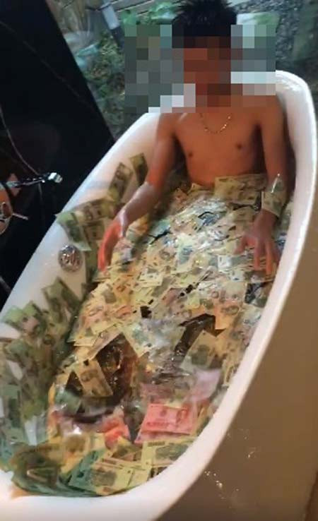 Trước đó, vào tháng 6, đoạn clip quay cảnh một chàng trai tắm trong tiền đã thu hút được rất nhiều sự quan tâm của dân mạng. (Ảnh chụp từ clip)