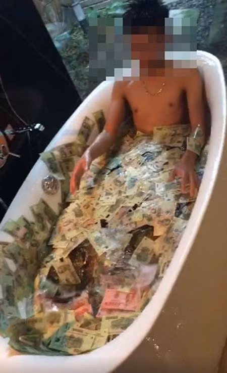 Trước đó, vào tháng 6, đoạn clip quay cảnh một chàng trai tắm trong tiền đã thu hút được rất nhiều sự quan tâm của dân mạng. (Ảnh chụp từ clip)