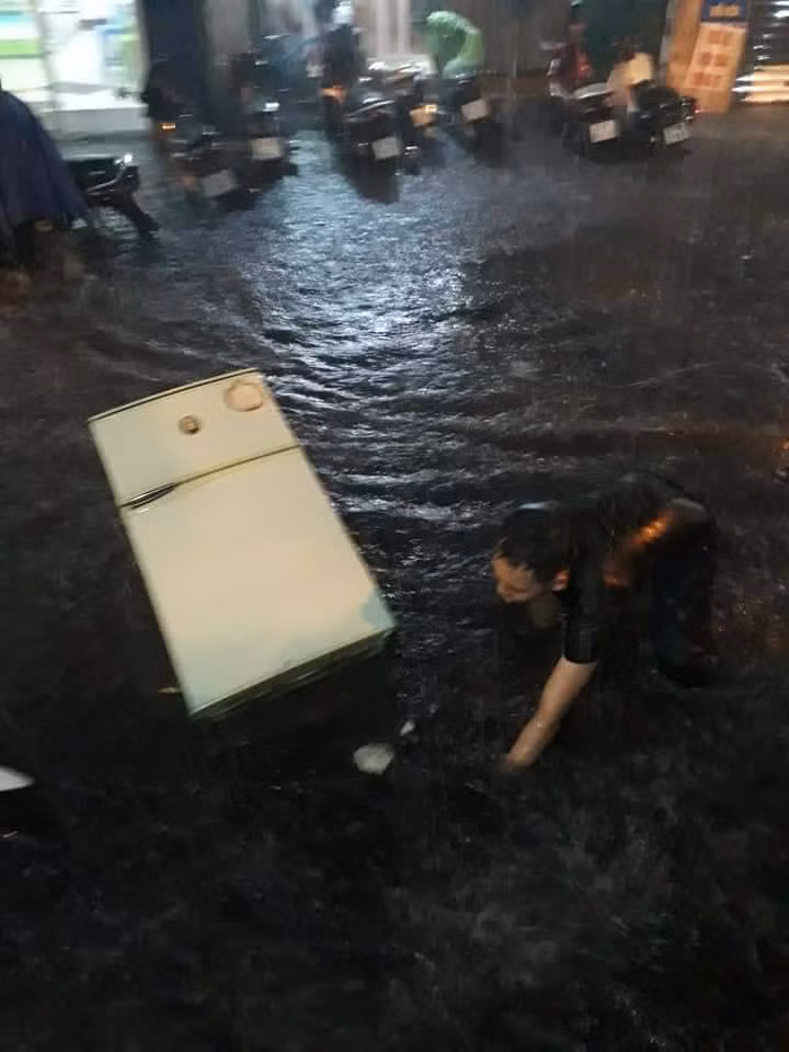 Để rã đông chiếc tủ lạnh của mình, một gia đình tại Hà Nội thậm chí đã phải sử dụng phương pháp ném nó ra trước cửa nhà nơi con phố lênh láng nước ngập.