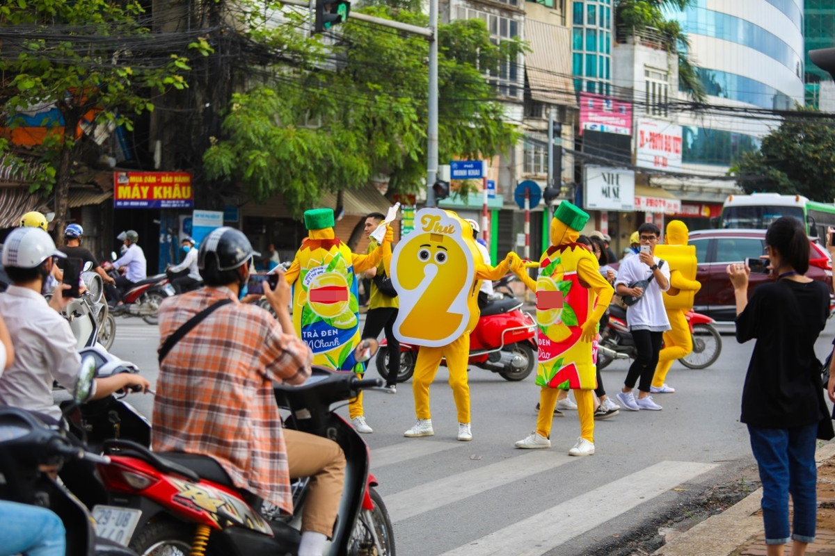 Những người đi xe máy, xe ô tô, xe buýt khi đứng chờ đèn đỏ không khỏi ngạc nhiên trước điều này, người đi bộ hay bán hàng quán xung quanh đường, cũng túm tụm lại xem màn quảng cáo bất chấp này.