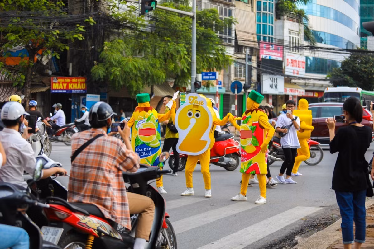 Những người đi xe máy, xe ô tô, xe buýt khi đứng chờ đèn đỏ không khỏi ngạc nhiên trước điều này, người đi bộ hay bán hàng quán xung quanh đường, cũng túm tụm lại xem màn quảng cáo bất chấp này.