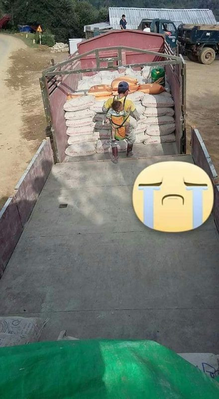 Giữa thời tiết nóng bức, thế mà người đàn ông với thân hình nhỏ nhắn gầy gò, bận trên người bộ quần áo đã bạc màu trên lưng địu đứa con nhỏ cần mẫn làm việc. Em còn bé ngủ say sưa, ngoan ngoãn nằm yên trên lưng.