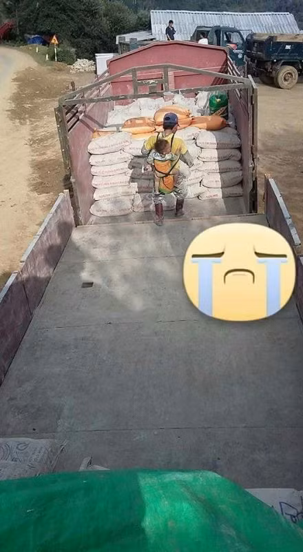 Giữa thời tiết nóng bức, thế mà người đàn ông với thân hình nhỏ nhắn gầy gò, bận trên người bộ quần áo đã bạc màu trên lưng địu đứa con nhỏ cần mẫn làm việc. Em còn bé ngủ say sưa, ngoan ngoãn nằm yên trên lưng.