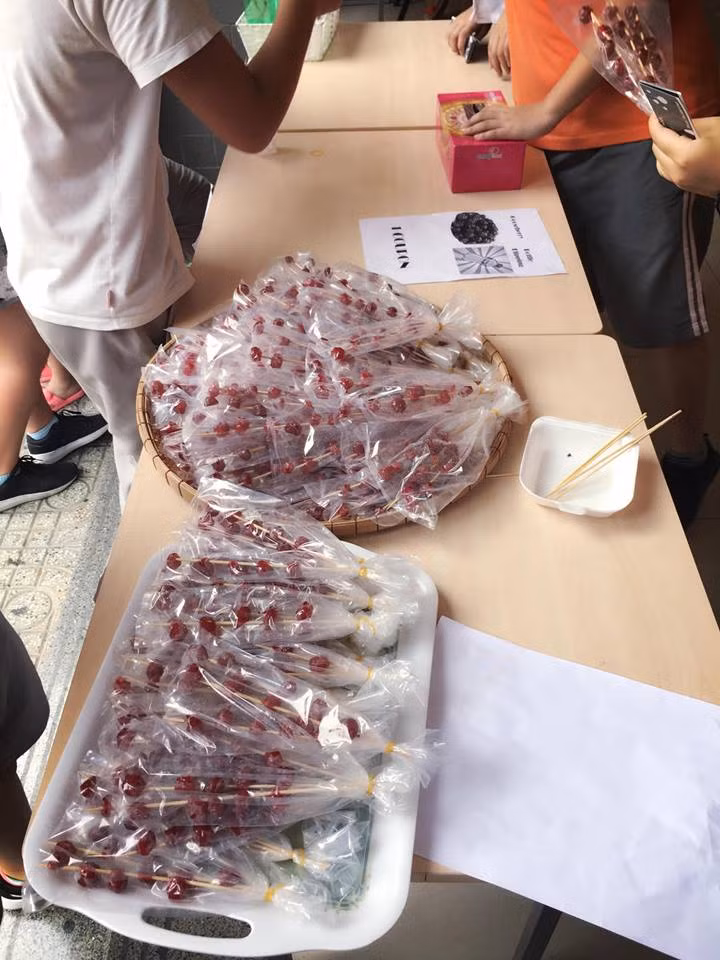 Ngoài bức ảnh dắt tay con tới trường, Công Vinh còn chia sẻ thêm những món đồ có trong buổi hội chợ từ thiện của trường Bé Gạo. Hình ảnh những quả chùm ruột xiên que cũng khiến Công Vinh nhớ về tuổi thơ khốn khó nơi xứ Nghệ.