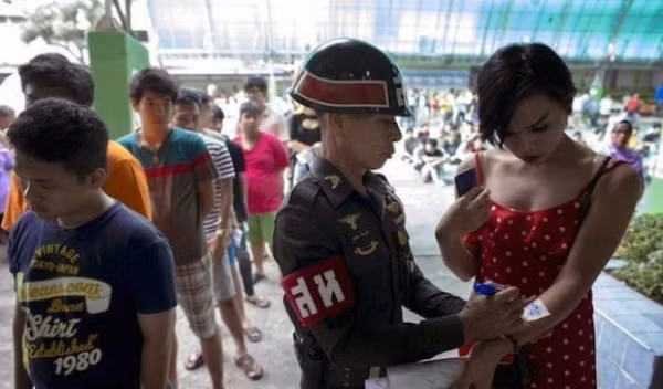 Một người chuyển giới được được sĩ quan ghi số thứ tự trên cánh tay.