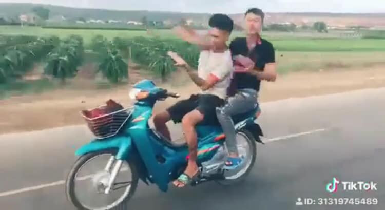 Cụ thể, khi điều khiển xe máy, 2 thanh niên đầu không đội mũ, thả tay để múa quạt giống Khá Bảnh.